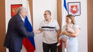 Сергей Аксёнов вручает сертификат на миллион рублей Константину и Яне Орловым. 