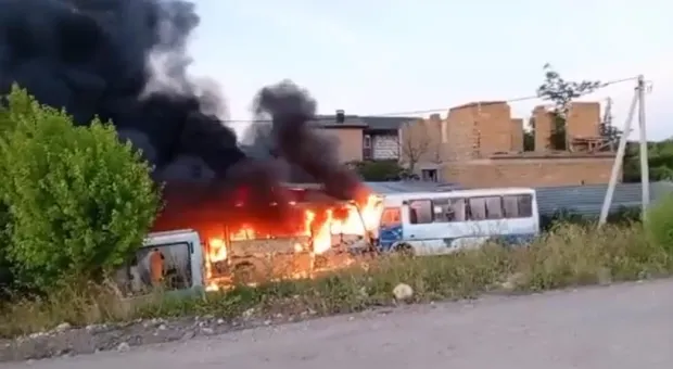 Пламя охватило припаркованный автобус, над ним поднимаются клубы дыма