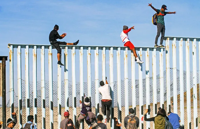 Первые беженцы попытались перелезть через ограждение на границе Мексики и США