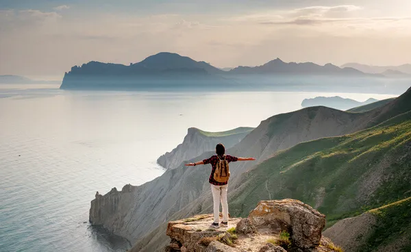 A young Asian woman with a backpack hiking in the summer.
